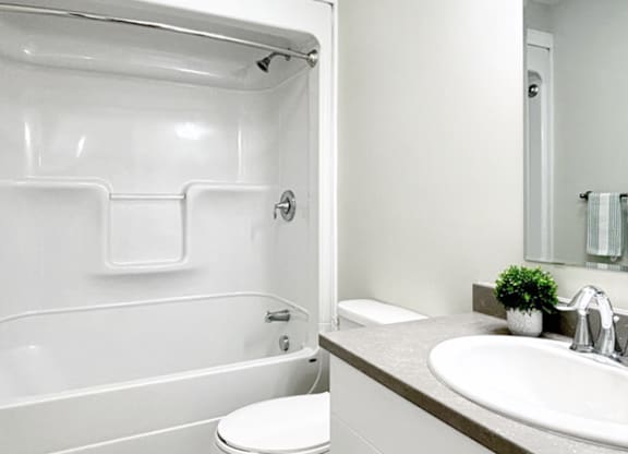 A white toilet sits in a white bathroom next to a white sink.