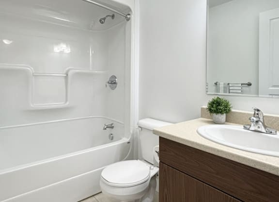 A white toilet sits next to a white bathtub in a bathroom.