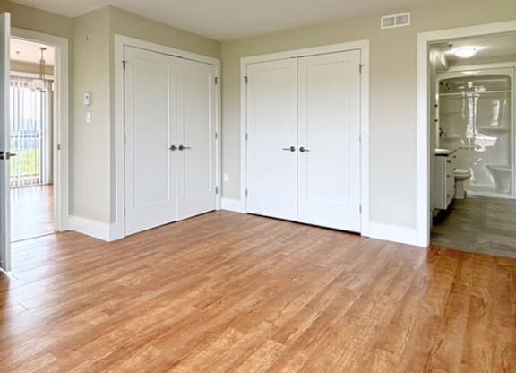 A room with white doors and wooden floors.