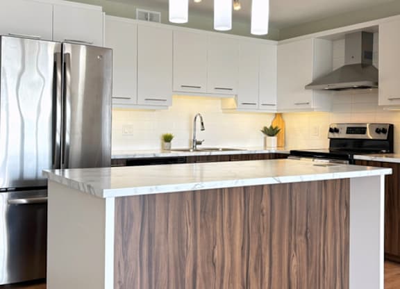 A modern kitchen with a wooden island and stainless steel appliances.
