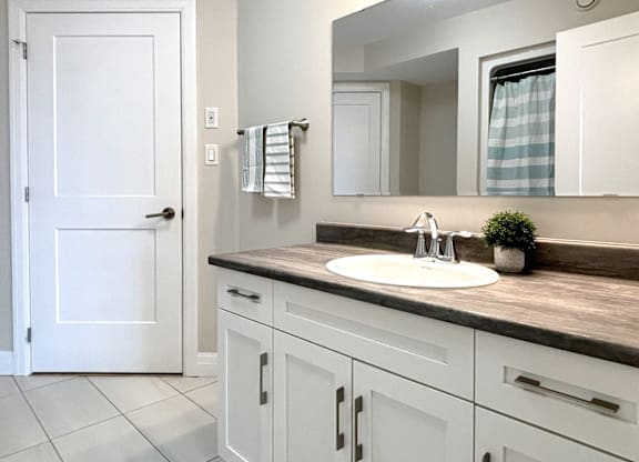 A bathroom with a white door, a sink, and a mirror.