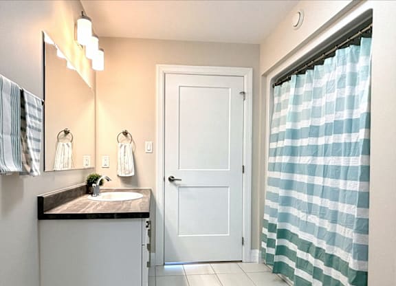 A bathroom with a sink, mirror, and shower curtain.
