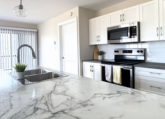 A kitchen with a marble countertop and stainless steel appliances.