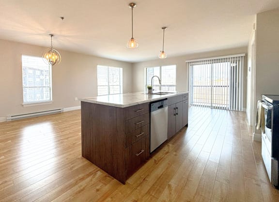 A kitchen with wooden floors and a large island with a sink.