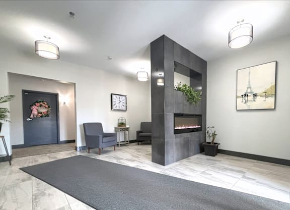 A modern living room with a grey rug and a fireplace.