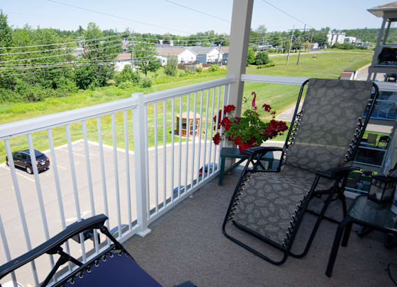 A chair and a table with a flower pot on a balcony.