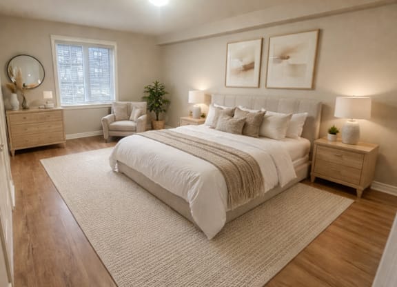 A bedroom with a large bed, a chair, and a potted plant.