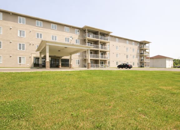 A large apartment complex with a car parked in the driveway.