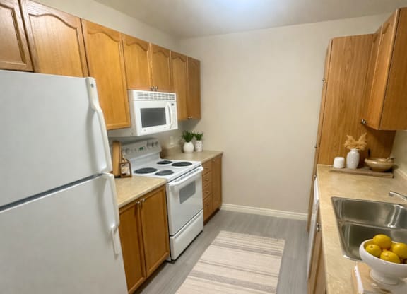 A kitchen with a white refrigerator, white stove, and wooden cabinets.