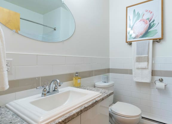 A bathroom with a sink, toilet, and a painting of a flower.