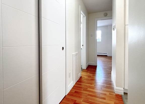 A long hallway with white walls and wood floors.