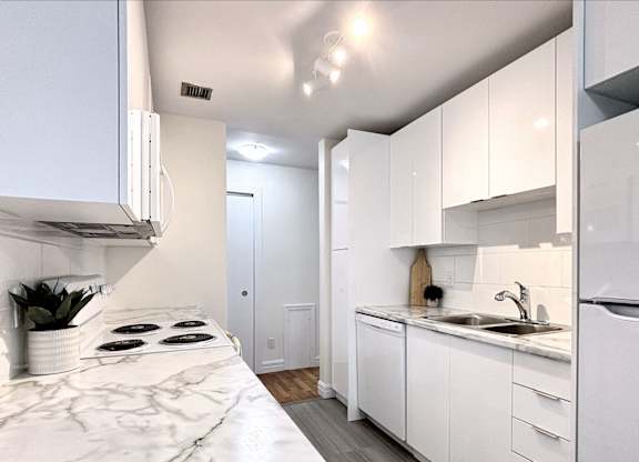 A kitchen with white cabinets and a marble countertop.