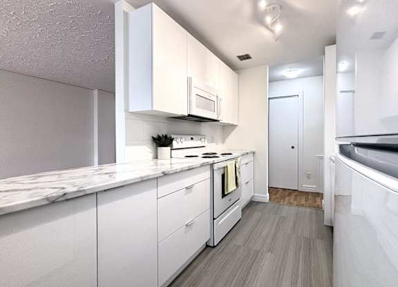 A modern kitchen with white cabinets and a marble countertop.