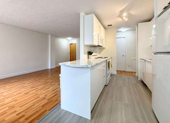 A kitchen with white appliances and wooden floors.