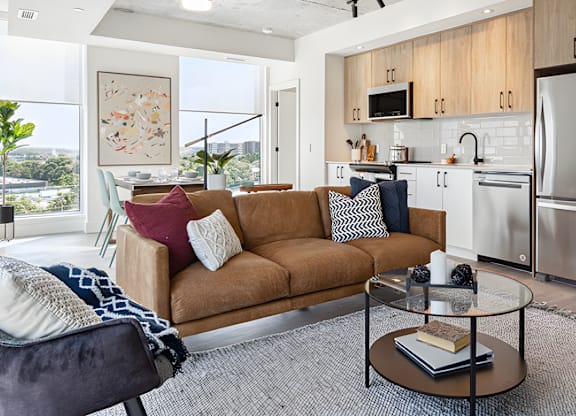A modern living room with a brown sofa and a glass coffee table.