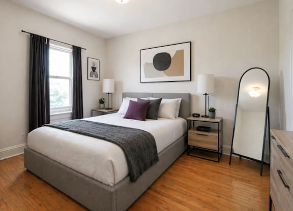 A bedroom with a large bed and a wooden floor.