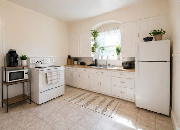 A white kitchen with a microwave on a stand.