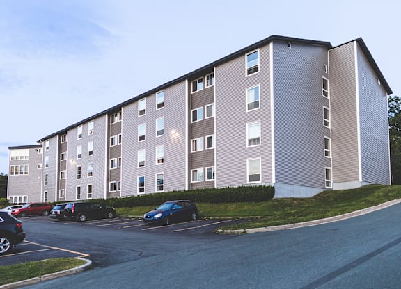 A large apartment building with a parking lot in front.