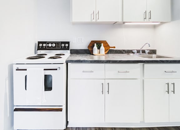 A white kitchen with a stove and cabinets.