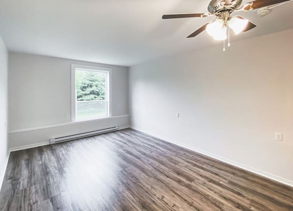 A room with a ceiling fan and wooden flooring.