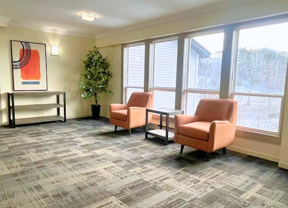 A room with two chairs and a table with a potted plant.
