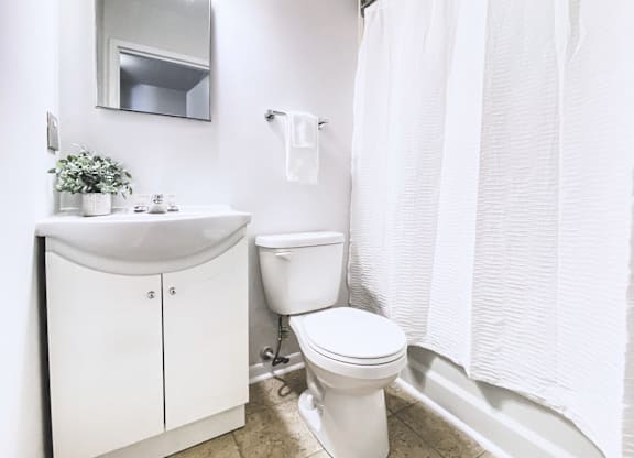 A white bathroom with a toilet, sink, and shower curtain.
