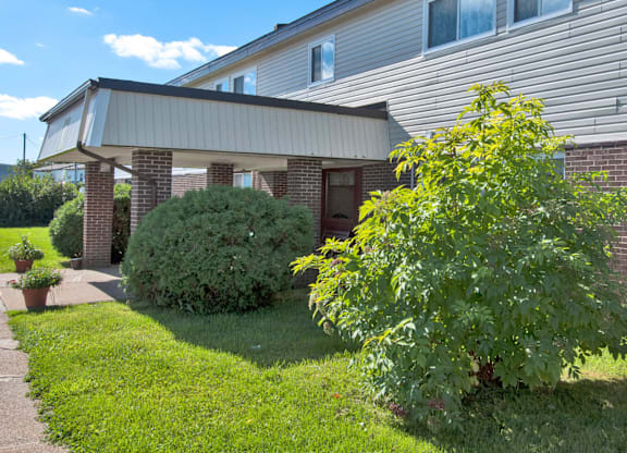 A house with a green lawn and a tree in front.