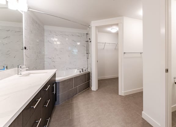 A bathroom with a marble tile wall and a white sink.