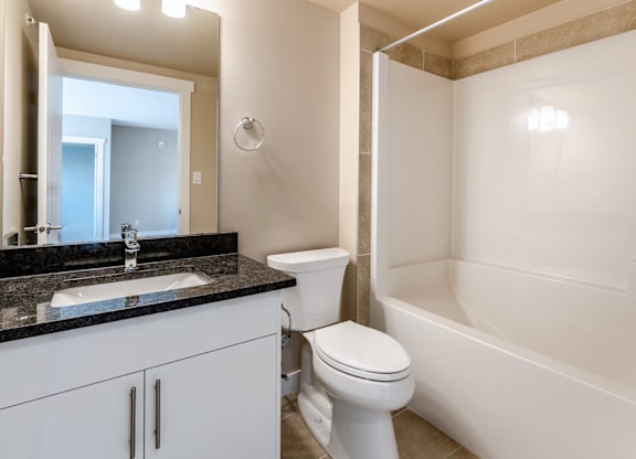 A white toilet sits next to a white bathtub in a bathroom.