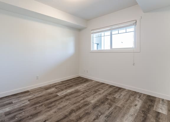 A room with a window and wooden flooring.