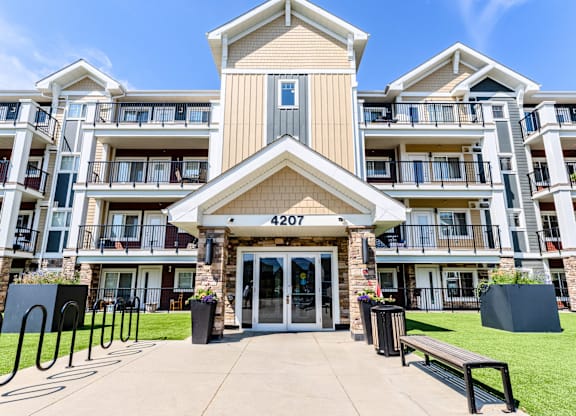 The image shows the front of apartment building number 4207 with a clear blue sky in the background.