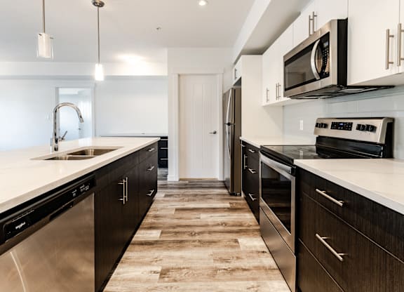 A modern kitchen with dark wood cabinets and stainless steel appliances.