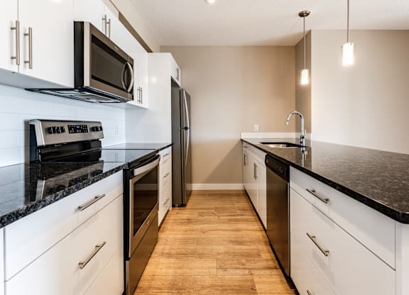 A kitchen with black countertops and white cabinets.