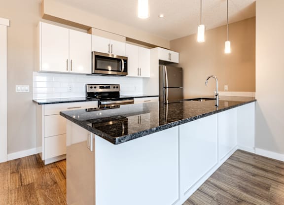 A kitchen with a black countertop and white cabinets.
