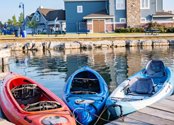 Two kayaks, one red and one blue, are docked at a wooden pier.