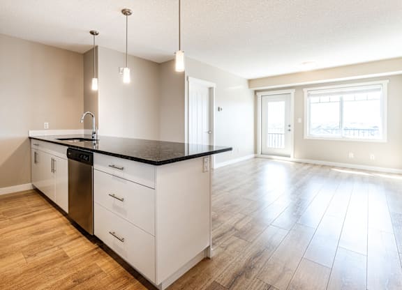 A kitchen with white cabinets and a black countertop.