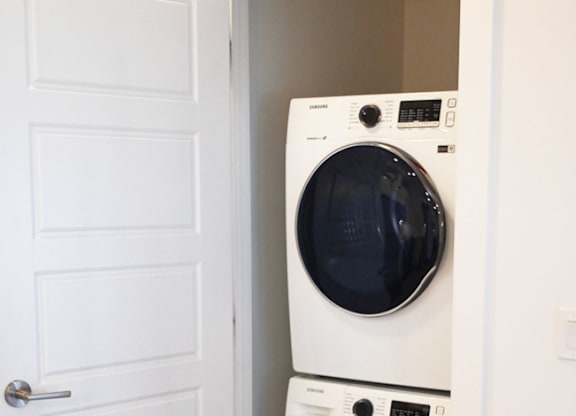Two white washing machines stacked in a doorway.