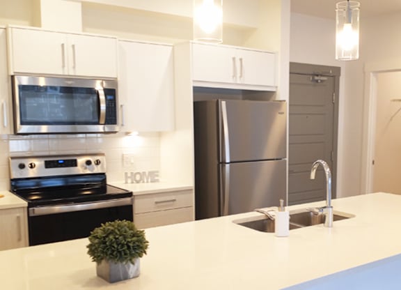 A modern kitchen with a stove, microwave, and refrigerator.