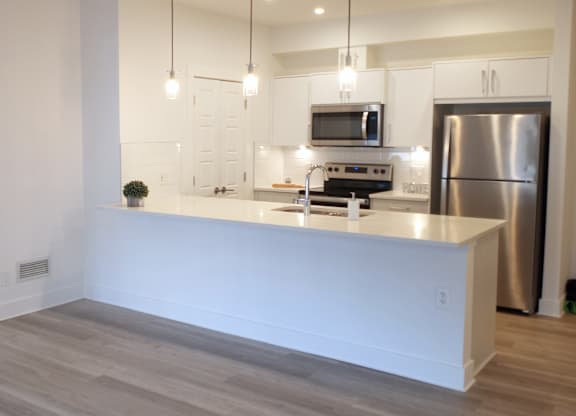 A modern kitchen with a white countertop and stainless steel appliances.