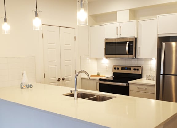 A kitchen with a sink, stove, and refrigerator.