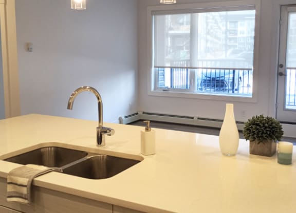 A kitchen counter with a sink and a window in the background.