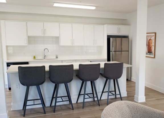 Four black barstools are placed in front of a white counter.