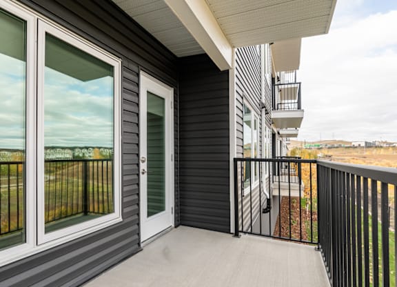 A balcony with a black railing and a white door.