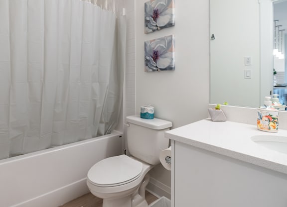 A white bathroom with a toilet, sink, and shower curtain.