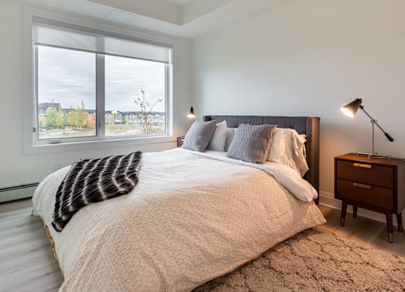 A bedroom with a large bed and a window overlooking a cityscape.
