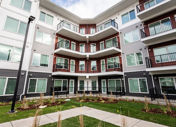 A modern apartment complex with balconies and a well-maintained lawn.