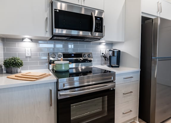 A modern kitchen with a stainless steel refrigerator, microwave, and oven.
