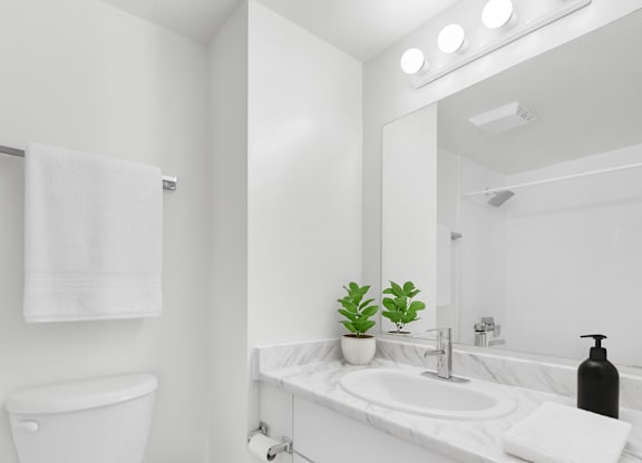 A white bathroom with a toilet, sink, and mirror.