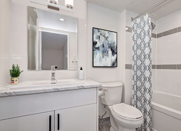A white bathroom with a toilet, sink, and shower.