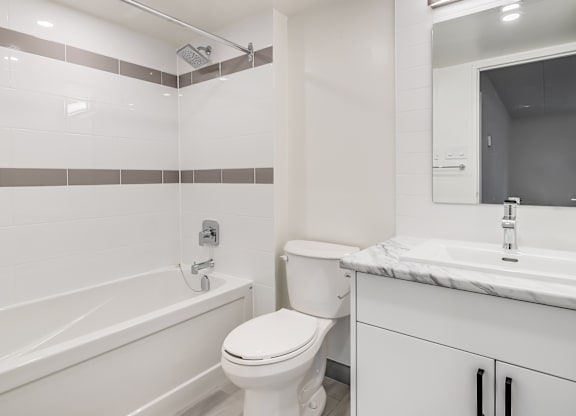 A white toilet sits next to a white bathtub in a bathroom.